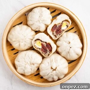 Banh bao steamed buns in a bamboo steamer basket. One cut in half to show inside.