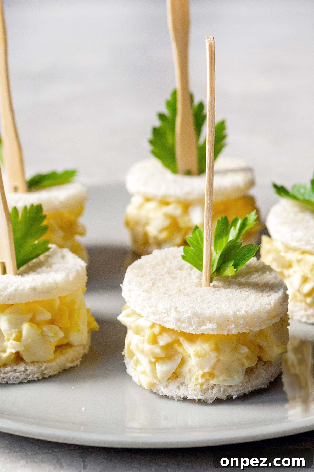 Creamy Egg Salad Tea Sandwiches Recipe 2 Egg salad tea sandwiches on a plate.