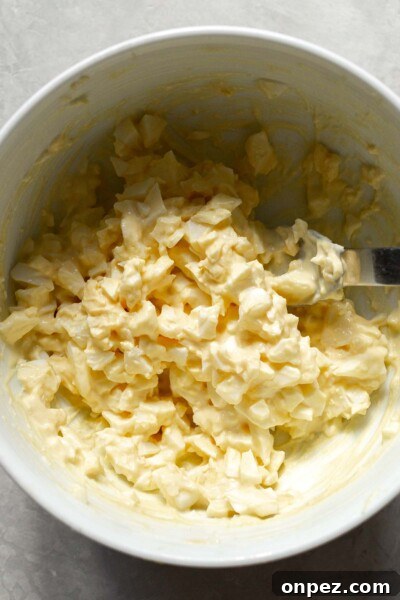 Creamy Egg Salad Tea Sandwiches Recipe 6 Chopped eggs, mustard, mayo, and salt in a bowl.