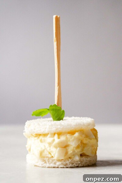 Creamy Egg Salad Tea Sandwiches Recipe 8 Egg salad sandwich with a skewer through it.