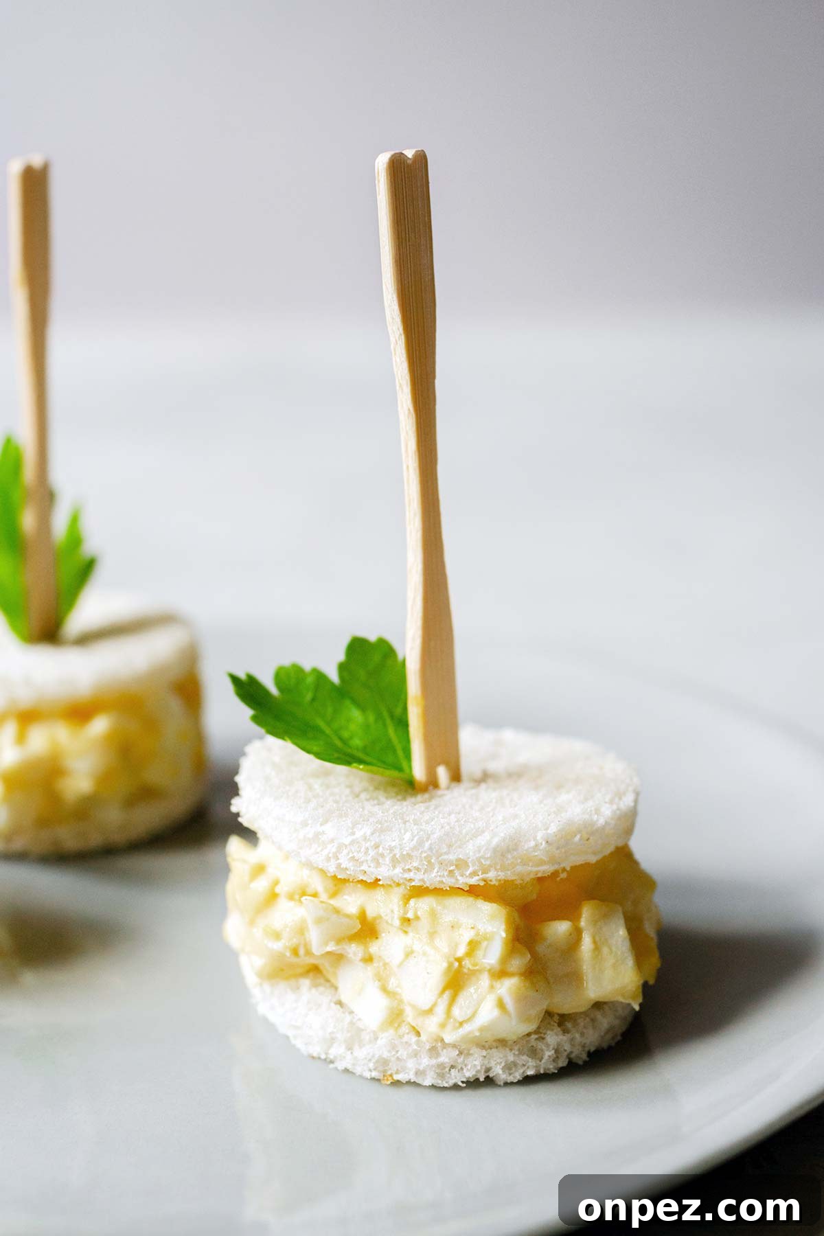 Creamy Egg Salad Tea Sandwiches Recipe 9 Egg salad tea sandwiches on a plate.