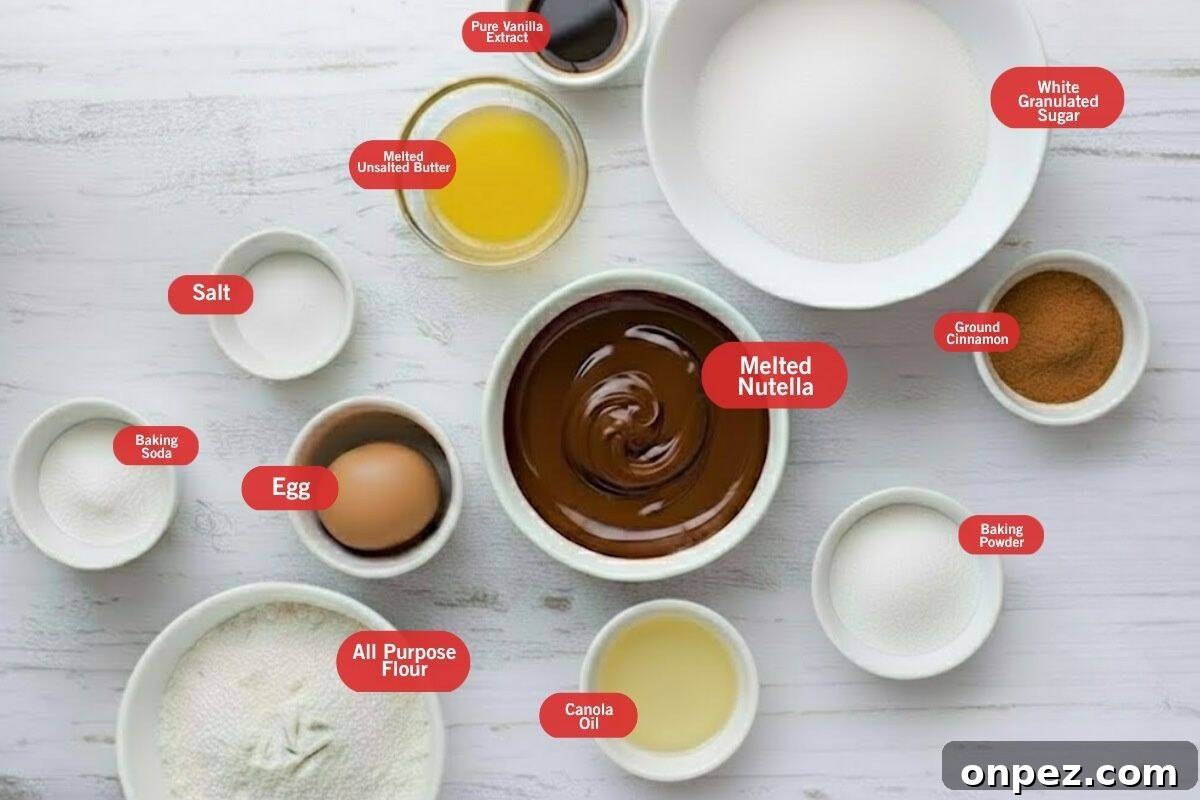 Flat lay of ingredient shot of baking soda and baking powder, all purpose flour, canola oil, baking powder, ground cinnamon, melted nutella, egg, salt, melted unsalted butter, pure vanilla extract, white granulated sugar