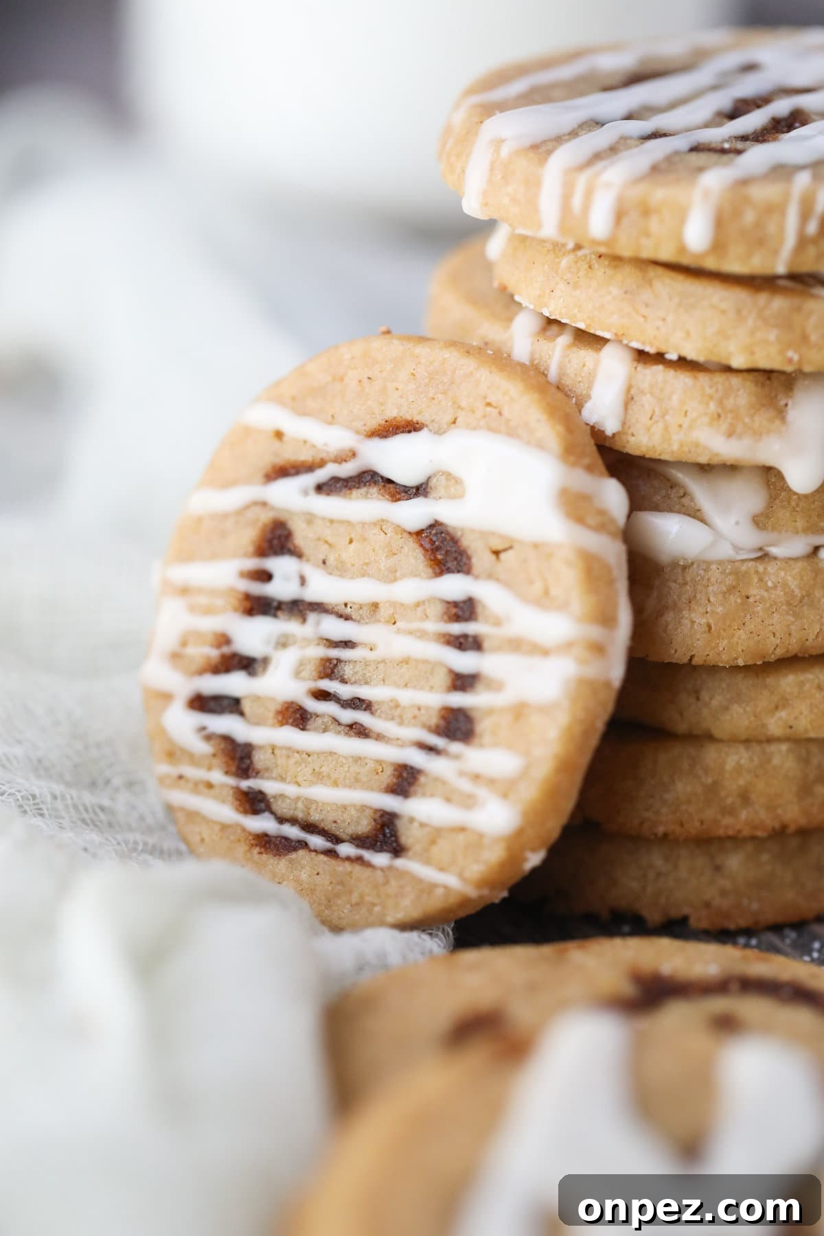 cinnamon roll cookie with vanilla glaze on a white surface.