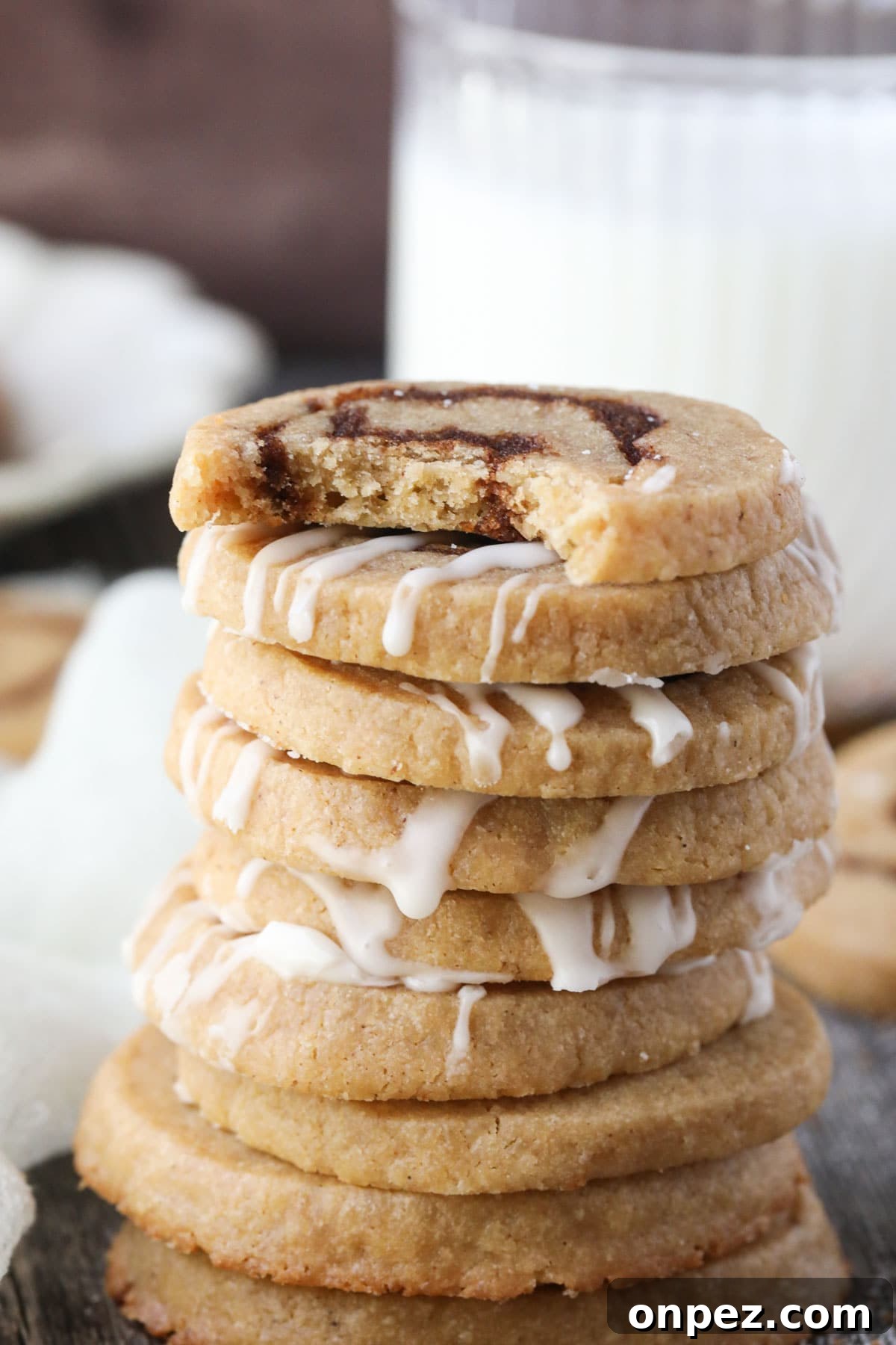 stack of cinnamon roll cookies with a bite taken out of the top cookie.