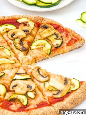 Half-eaten pizza with mushrooms and zucchini.