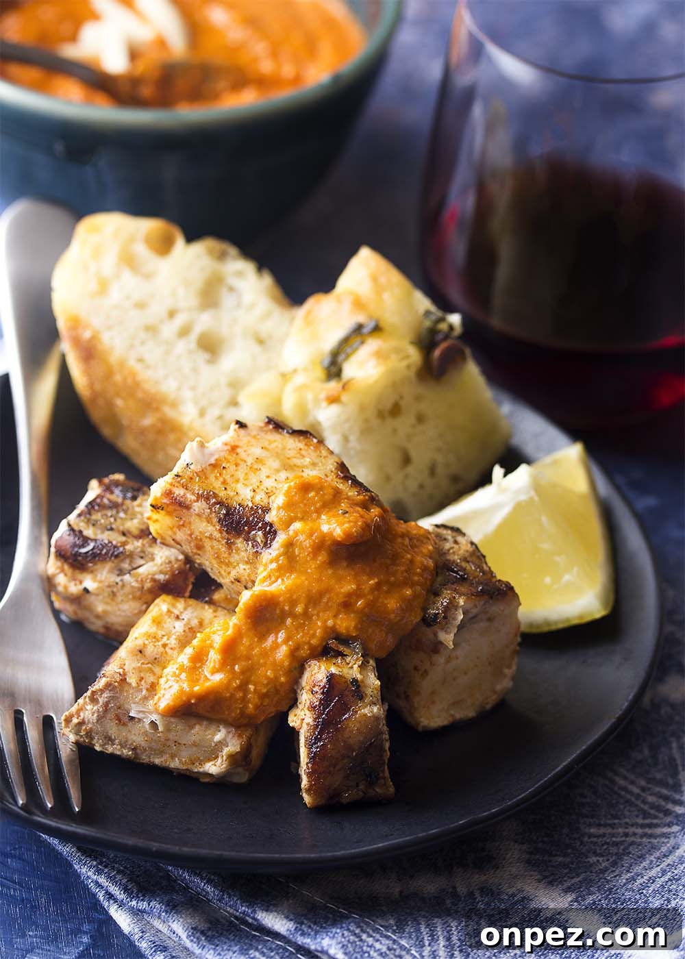 Grilled paprika-rubbed swordfish kebabs served with sauce. Juicy grilled cubes of swordfish piled on a plate and topped romesco sauce.