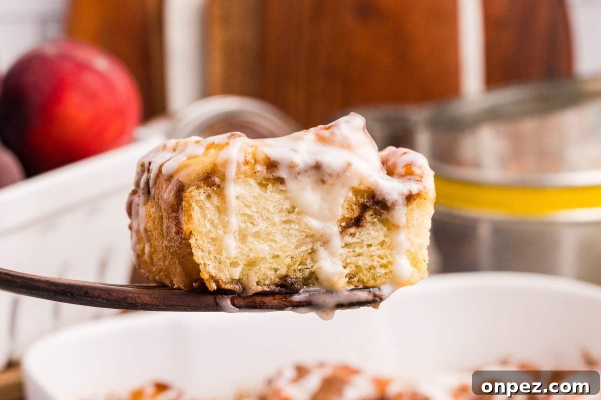 Single peach cobbler cinnamon roll on a wooden spatula.