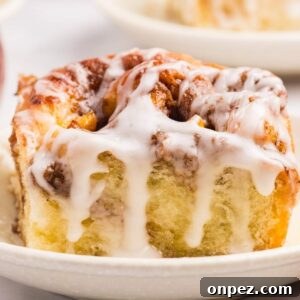 Peach cobbler cinnamon roll on a small plate with icing.