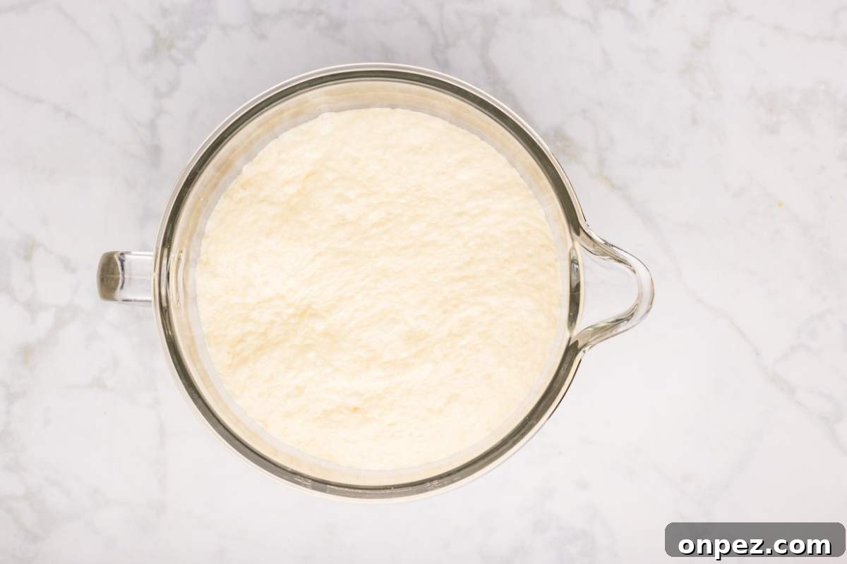 Dough doubled in size in a glass mixing bowl.