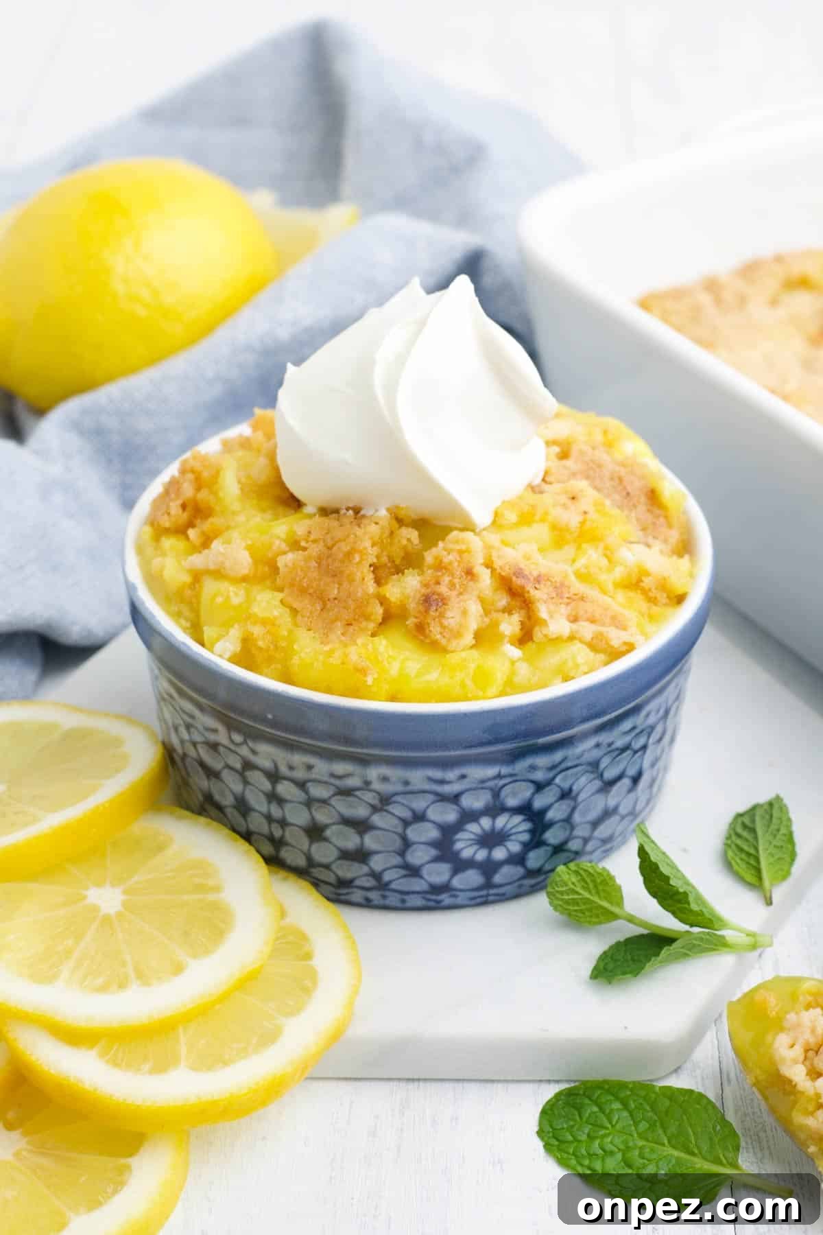 Quick Lemon Dump Cake Recipe 2 Lemon dump cake served up in a small blue bowl topped with whipped cream.