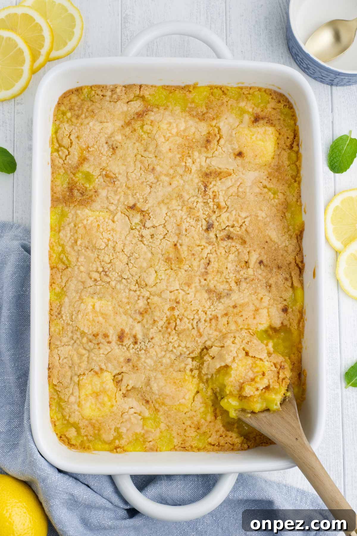 Quick Lemon Dump Cake Recipe 4 Baked lemon dump cake with a wooden spoon scooping a serving out.
