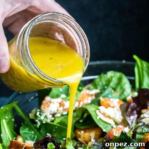 Honey Dijon Vinaigrette dressing being poured onto a bowl of salad.