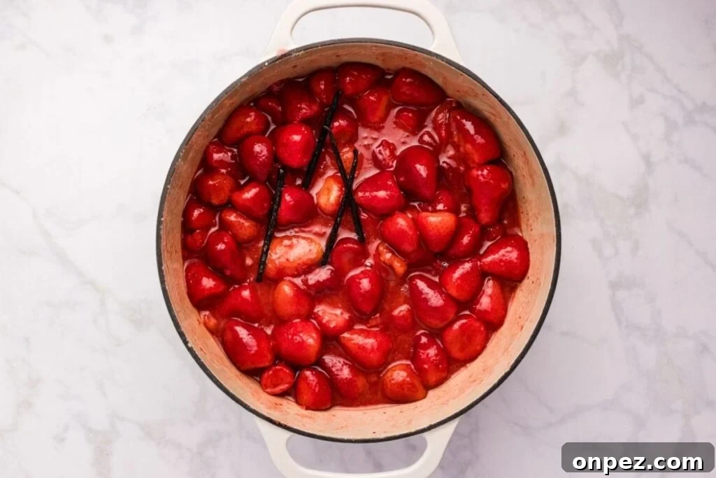 Homemade Strawberry Butter Canning Recipe and Tips 5 Strawberries simmering with vanilla beans in a pot of red liquid.
