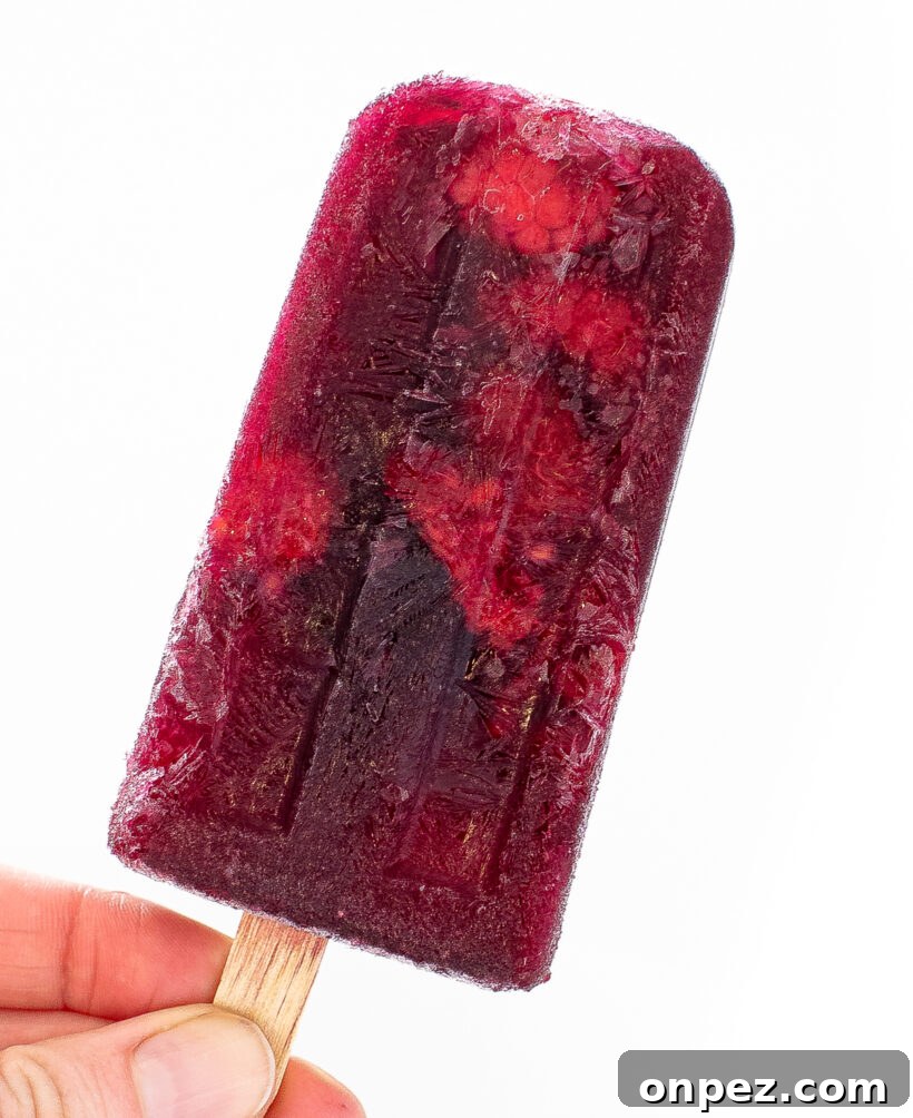 Sangria Popsicle Recipe: Refreshing Wine Pops for Summer 3 Hand holding a red sangria popsicle.