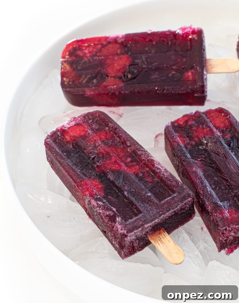 Sangria Popsicle Recipe: Refreshing Wine Pops for Summer 6 Raspberry popsicles on a bed of ice in a white bowl.
