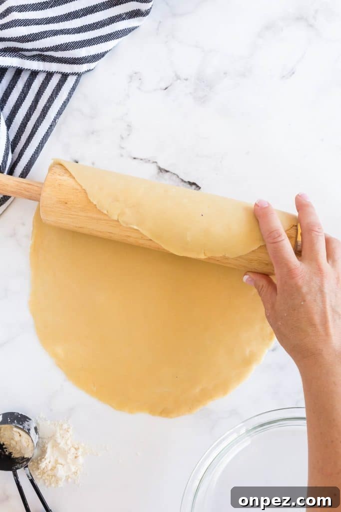 Perfect Homemade Pie Crust Recipe: Flaky and Foolproof 12 picking up the circle of dough with a rolling pin