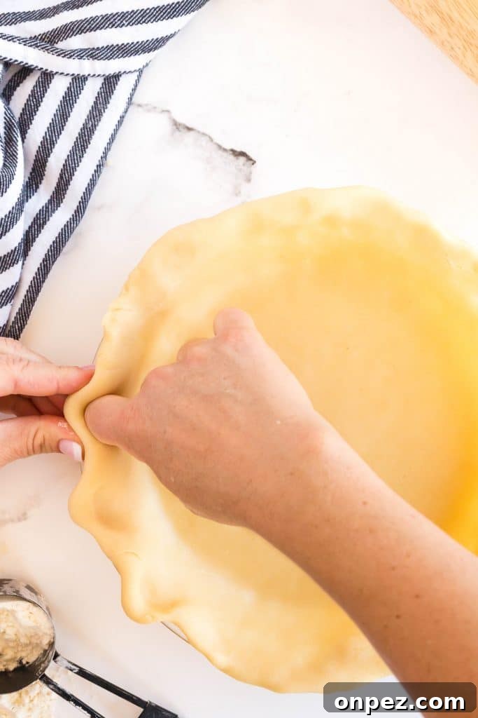 Perfect Homemade Pie Crust Recipe: Flaky and Foolproof 14 making a 'u' on the edges of the pie crust dough with two fingers