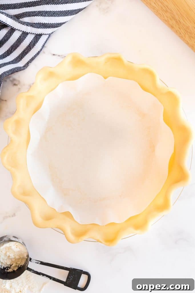 Perfect Homemade Pie Crust Recipe: Flaky and Foolproof 16 Uncooked pie crust with parchment paper on top of a pie plate