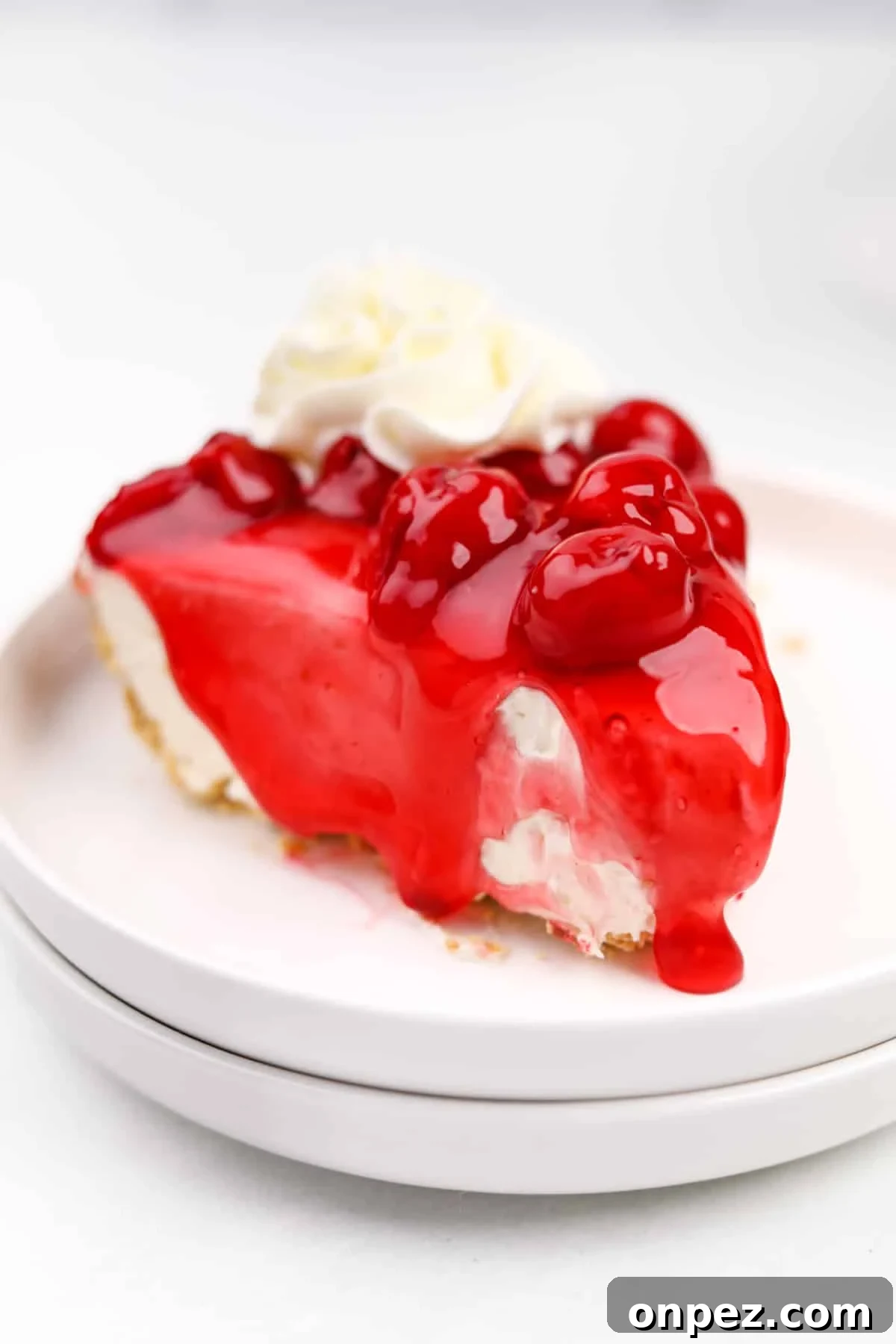 A slice of cheesecake topped with cherry topping and whipped cream.