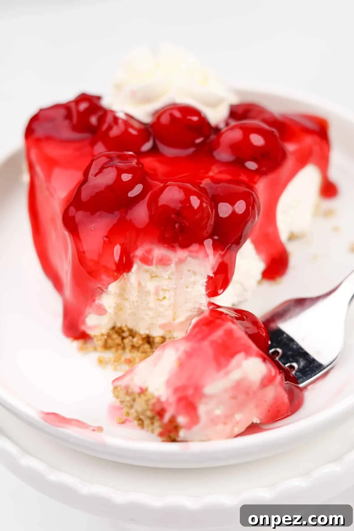 A close up of a slice of cheesecake pie topped with a cherry glaze.
