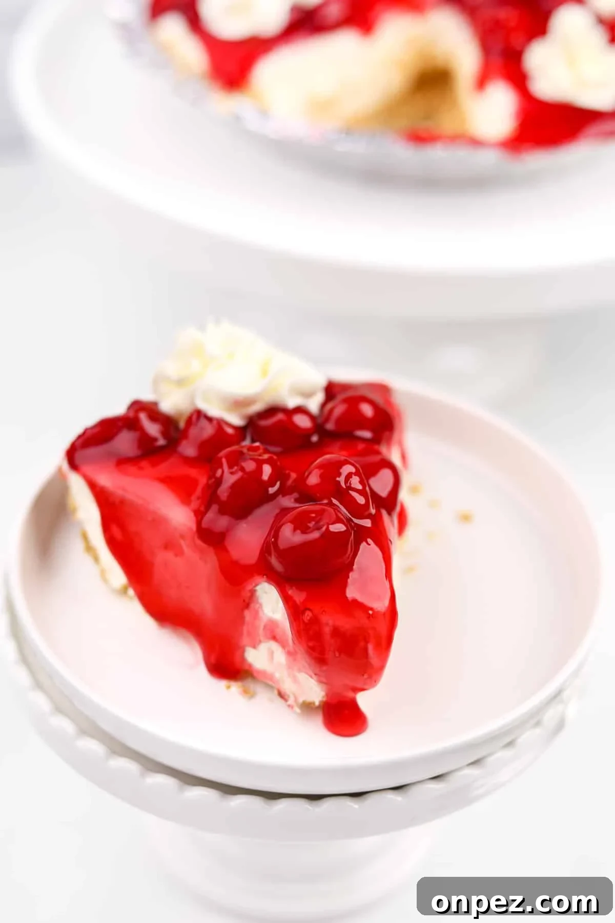 A slice of cheesecake topped with cherries and a glaze.