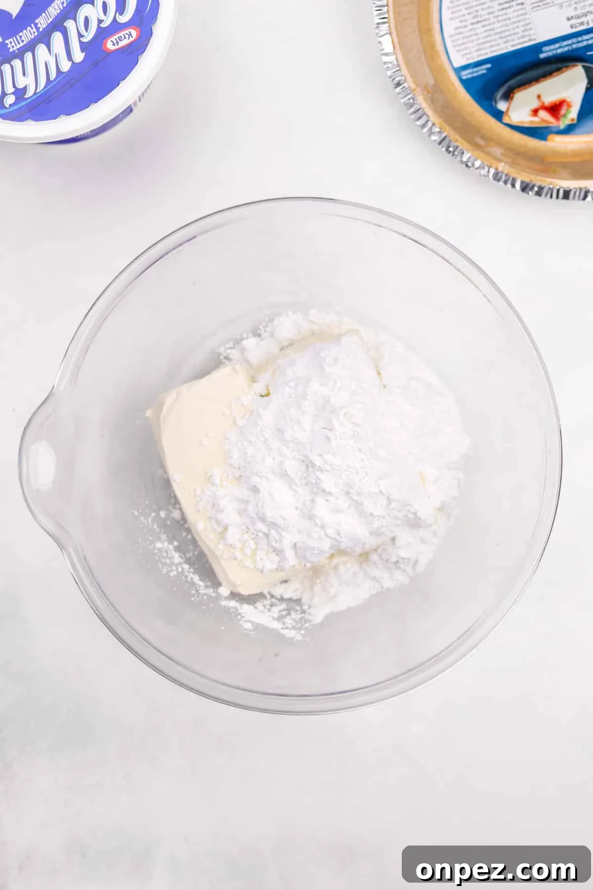 A bowl with cream cheese and powdered sugar in it.