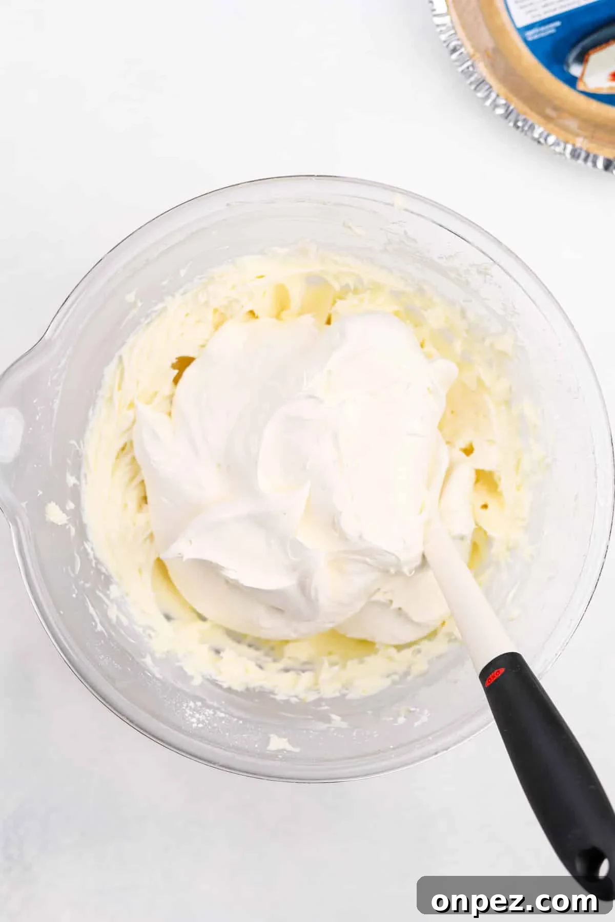 Adding thawed whipped topping to a cream cheese filling.