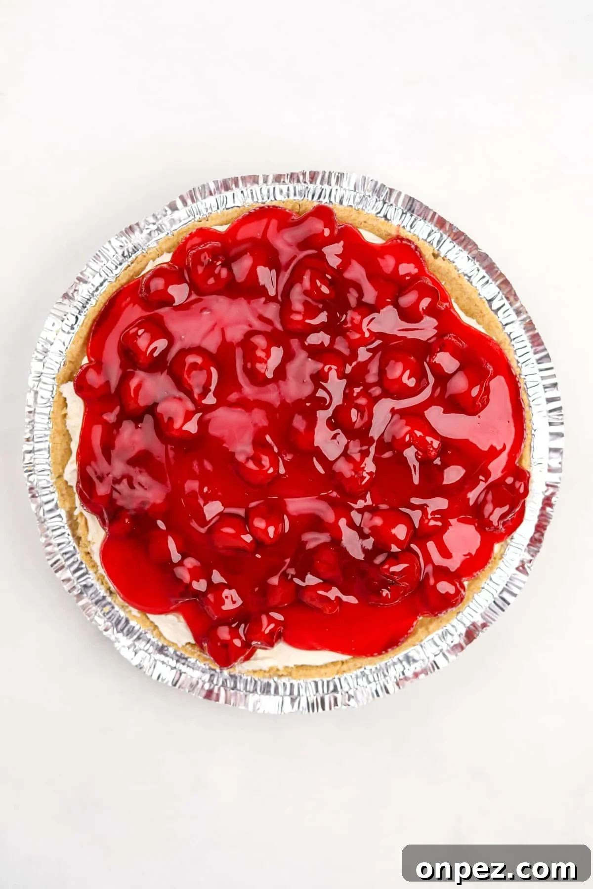 A cheesecake pie topped with cherry pie filling.