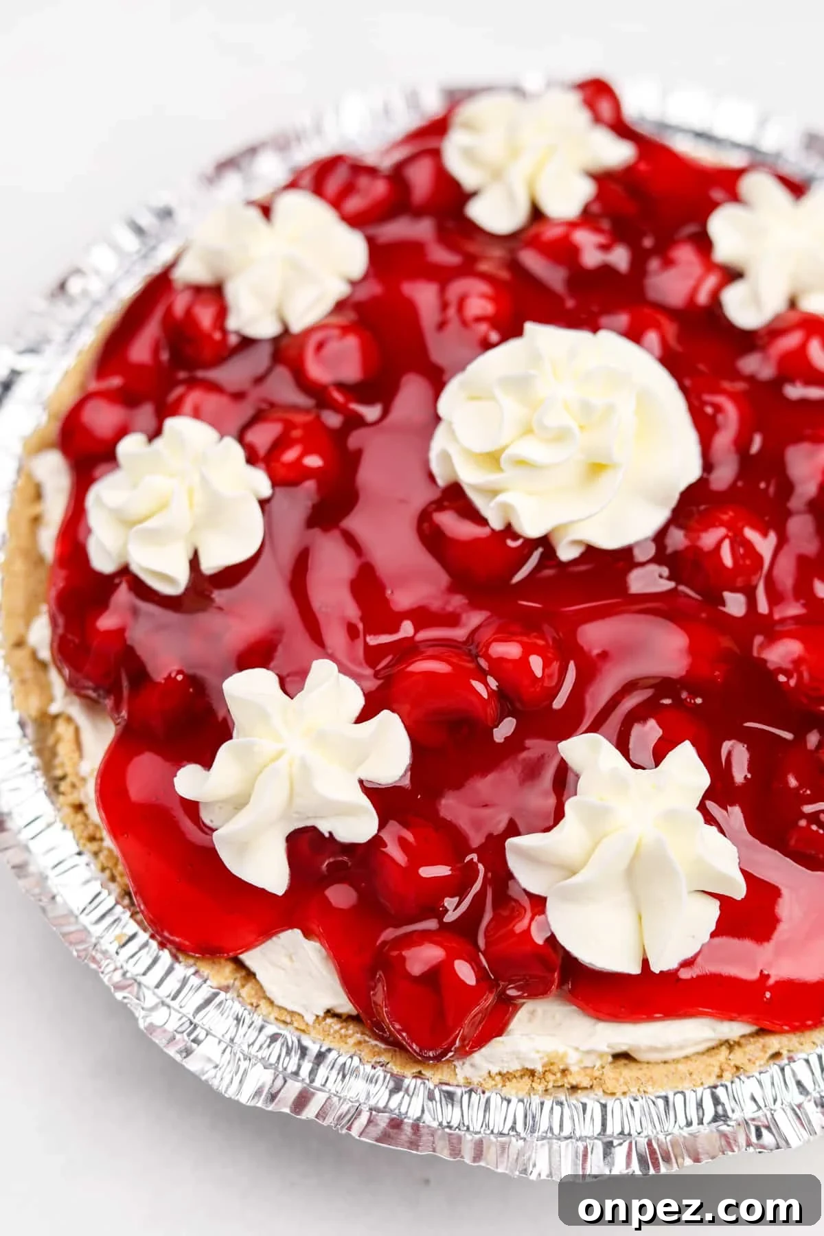 A cherry cheesecake topped with dollops of whipped cream.