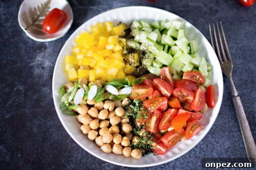 A bowl of chickpea salad with peppers and tomatoes