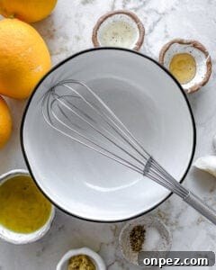 ingredients for lemon dressing placed around a white bowl and whisk