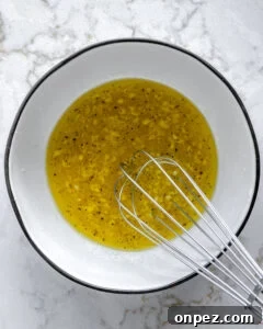 Bright Lemon Vinaigrette for Salads & Marinades 7 process of whisking lemon dressing ingredients together in white bowl against white background
