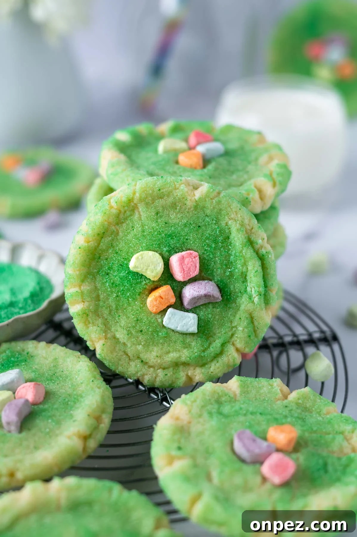 St Patricks Day Sugar Cookies with Festive Green Icing 2 green sugar cookies on a cooling rack with a glass of milk in the background