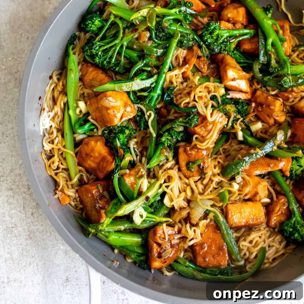 Teriyaki salmon noodles in a sauté  pan with ingredients inside. 