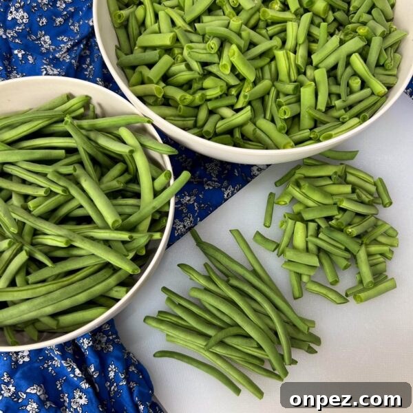 How to Freeze Green Beans for Freshness All Year 2 green beans trimmed, some cut, some long on cutting board and in bowls