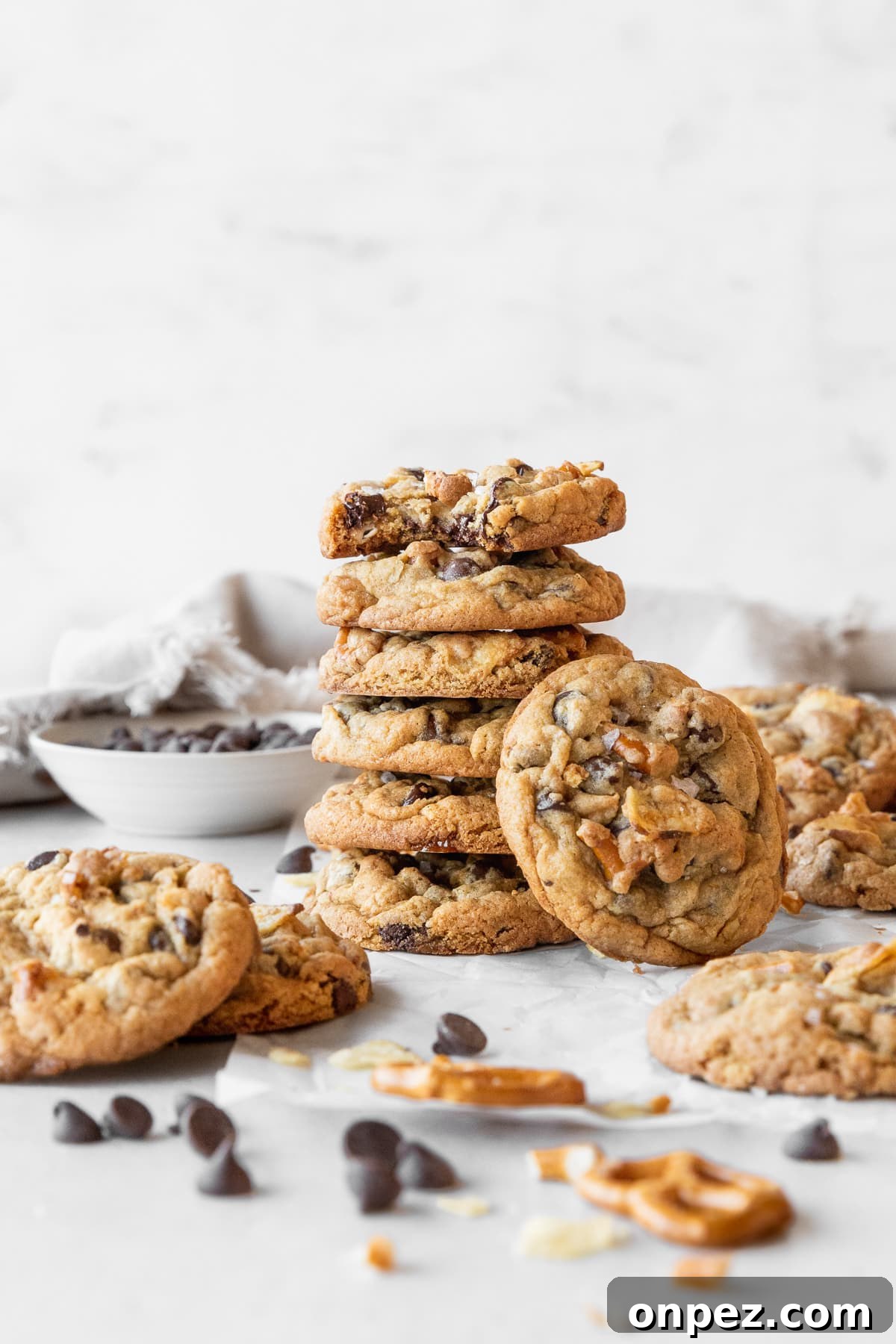 A stack of kitchen sink cookies on a light grey surface surrounded by more cookies.