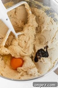 Vanilla paste and an egg added to the creamed butter in a metallic bowl.