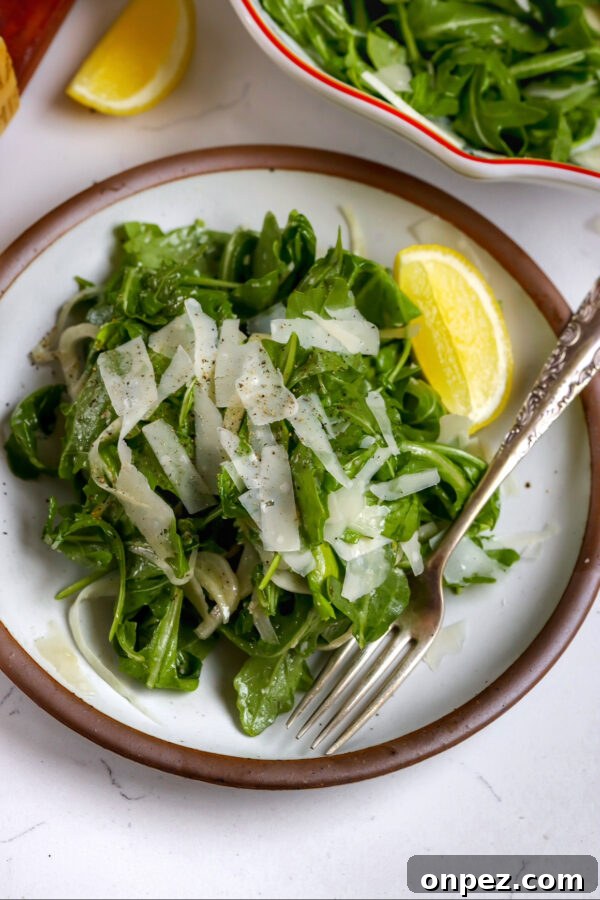 Arugula fennel salad with honey dijon dressing and lemon wedge.