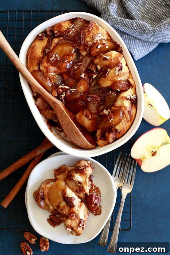 An overhead view of an Apple Pie Biscuit Casserole with a wooden spoon and a plate on a wire cooling rack.
