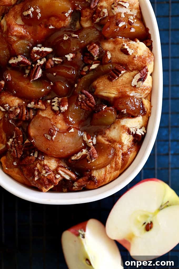 Apple Pie Biscuit Casserole in a white baking dish surrounded by sliced apple.