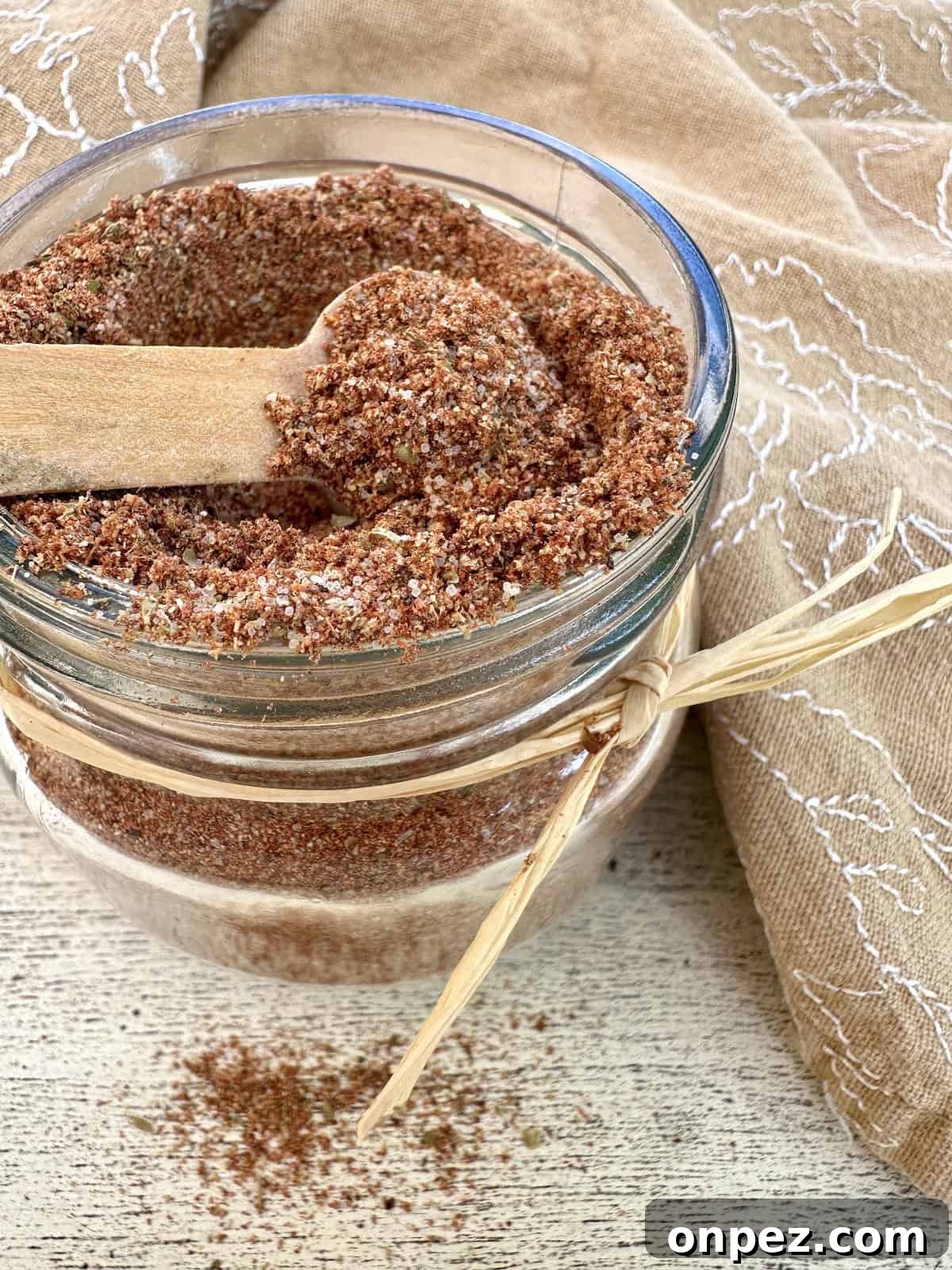 DIY Taco Seasoning Mix: Homemade Spice Blend 2 A small jar full of taco seasoning with a spoon on top and a napkin.