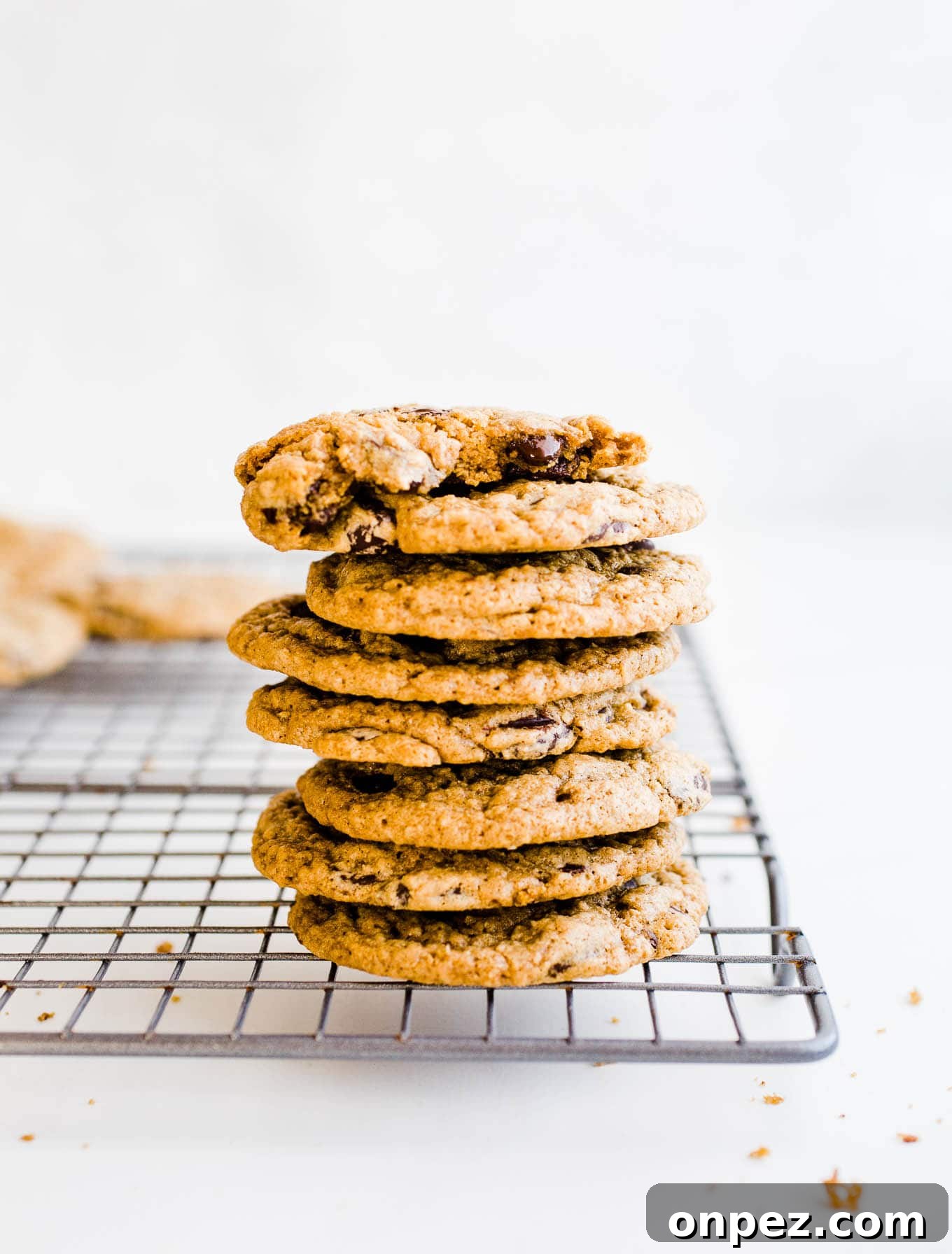 Chewy Gluten Free Vegan Chocolate Chip Cookies 4 Cookies with chocolate morsels stacked on a wire rack.