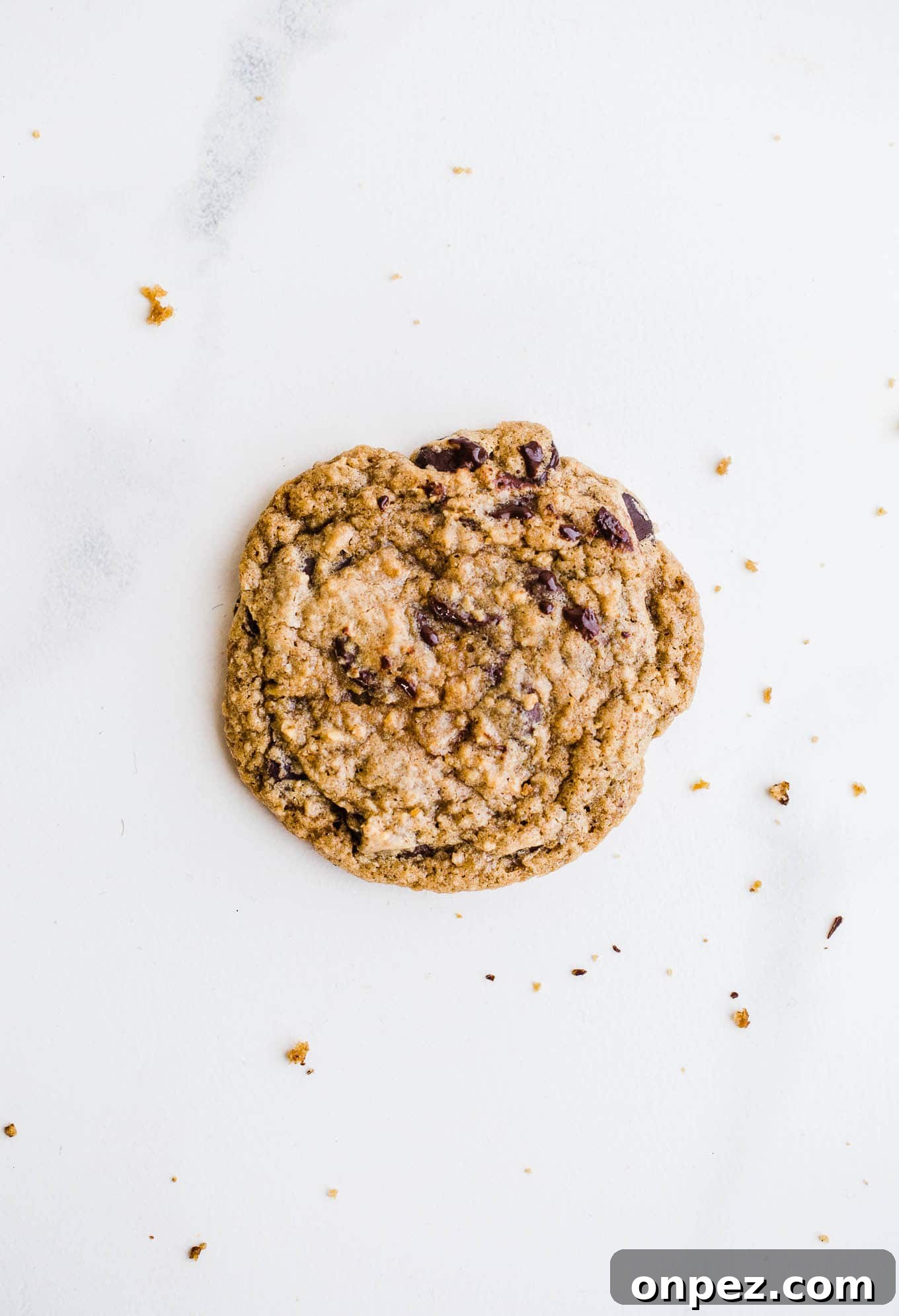 Chewy Gluten Free Vegan Chocolate Chip Cookies 5 One cookie with chocolate chips on a marble background.