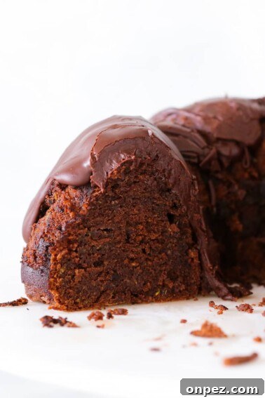 Mardi Gras Bundt Cake with Colorful Glaze 9 Chocolate Zucchini Cake fudge glaze sliced on cake stand.