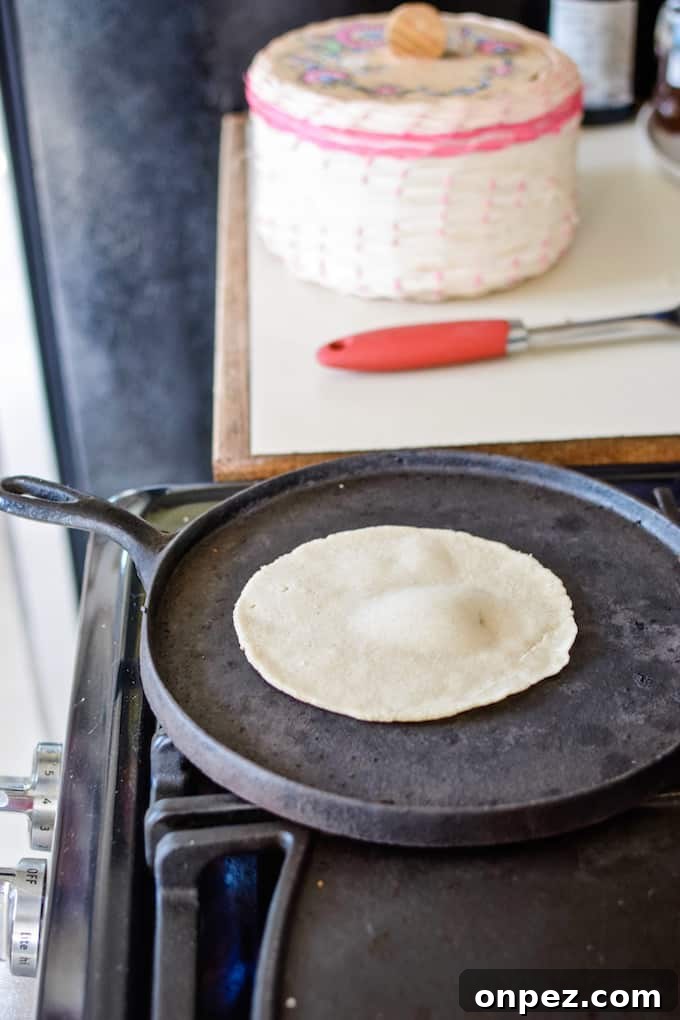 How to Make Authentic Corn Tortillas at Home 5 A tortilla cooking on a black pan on the stove