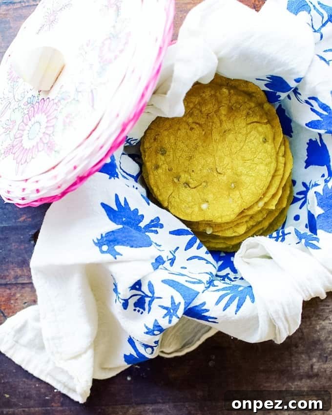 How to Make Authentic Corn Tortillas at Home 7 Yellow turmeric tortillas in a tortilla warmer on top of a white and blue towel.