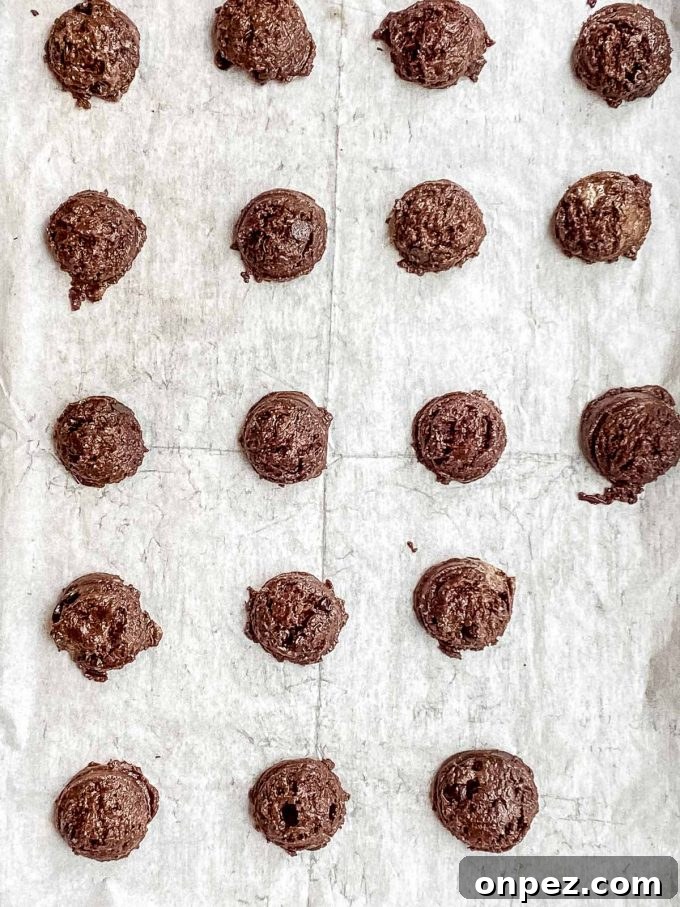 Scooped chocolate chip cookie dough on a parchment lined baking sheet