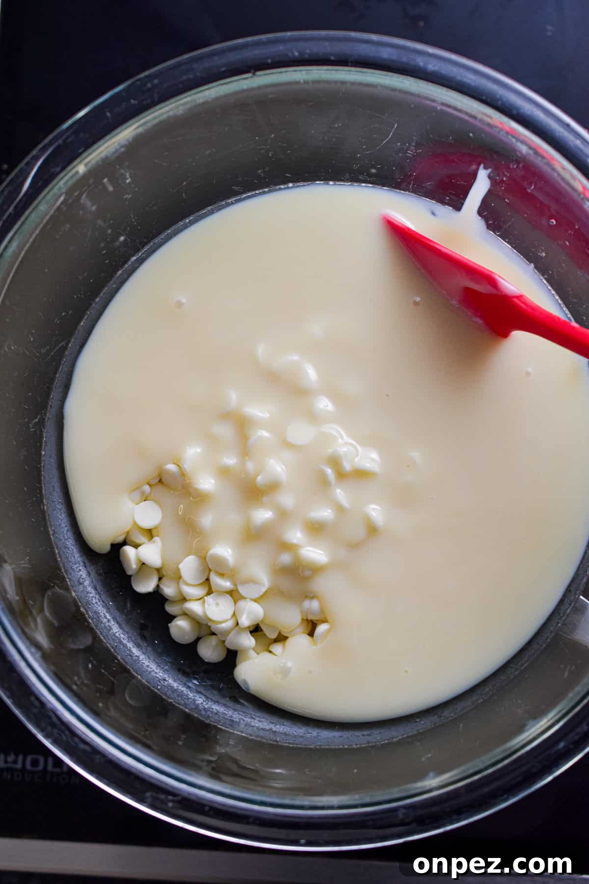 The white chocolate chips are in a glass bowl in a double boiler.