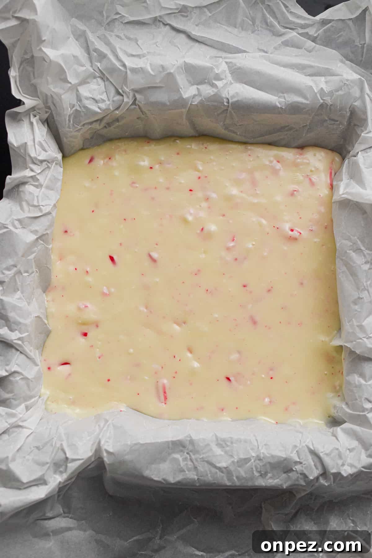 The fudge is poured into the square pan.