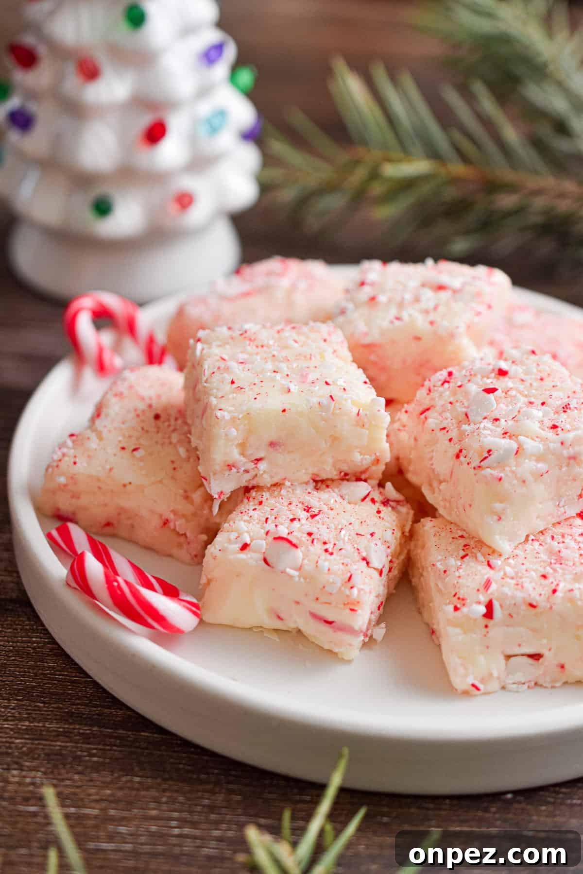 A white tree is in the background of the plate covered with white chocolate peppermint fudge.